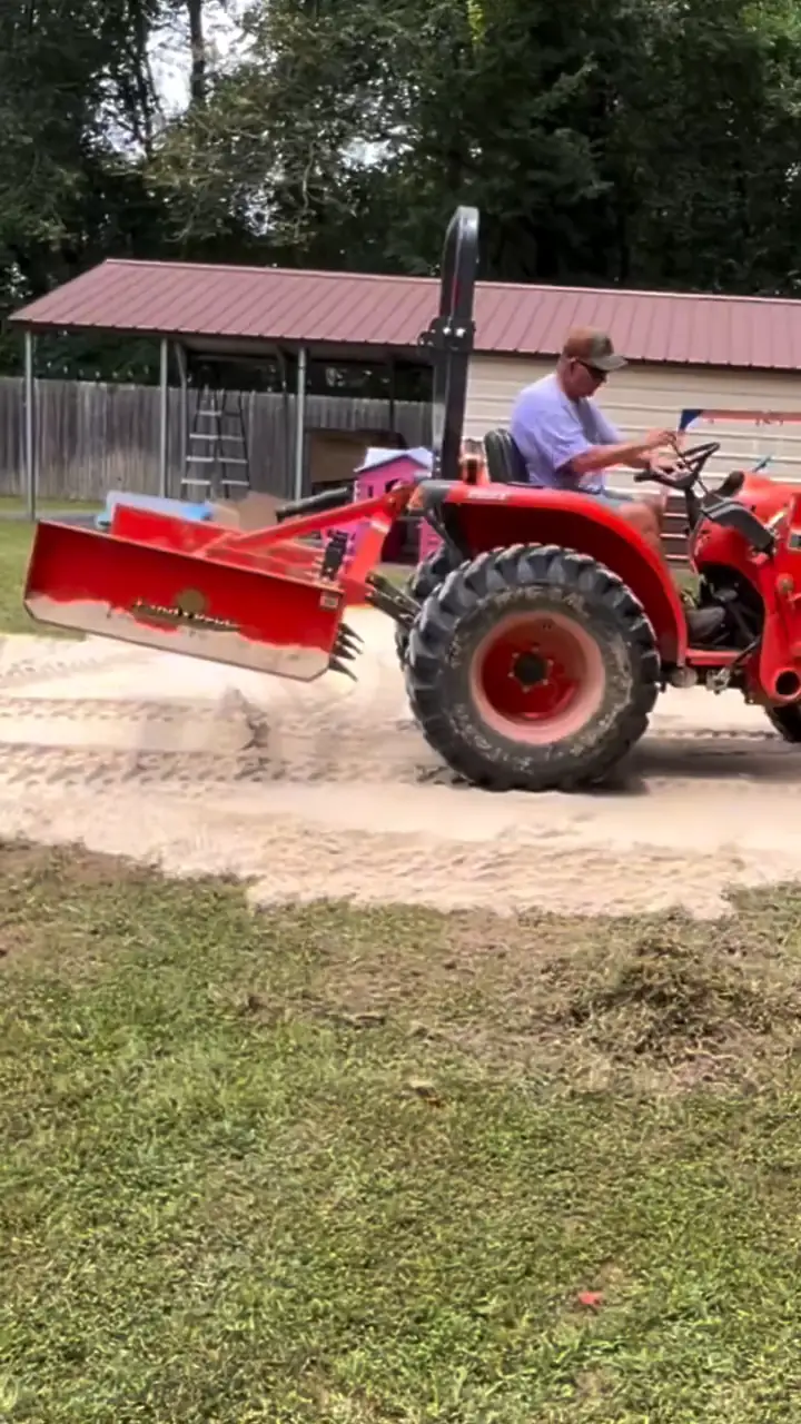 Tre grading a lot on a red tractor with a box blade